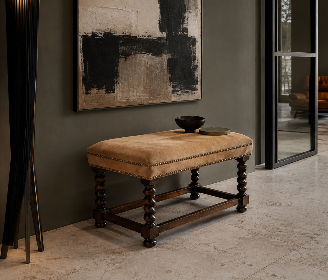 Beige upholstered bench with dark twisted legs in a modern hallway, topped with a bowl and a round coaster beneath an abstract painting.